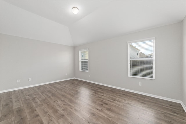 spare room featuring hardwood / wood-style floors and vaulted ceiling