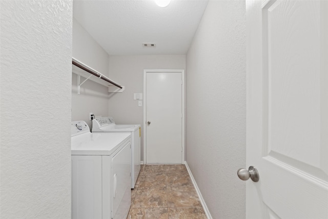 laundry room with a textured ceiling and washer and clothes dryer