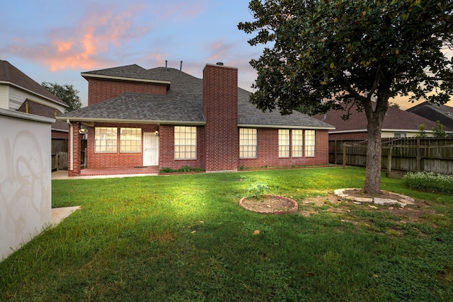 back house at dusk with a yard and a patio area