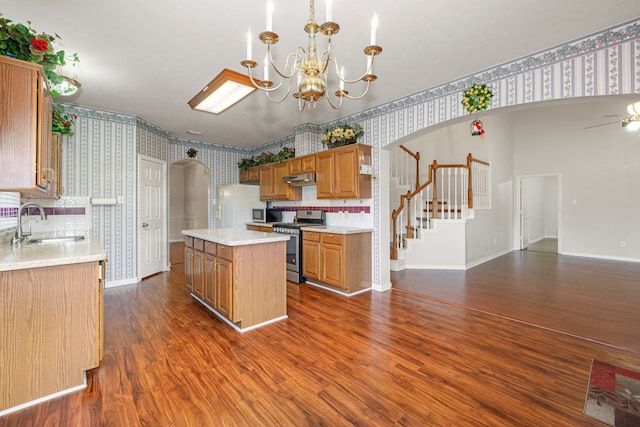 kitchen featuring pendant lighting, dark hardwood / wood-style flooring, stainless steel range with gas cooktop, a kitchen island, and sink