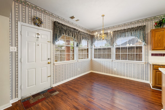 unfurnished dining area with dark wood-type flooring and a notable chandelier