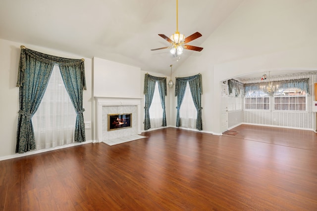 unfurnished living room featuring vaulted ceiling, a tiled fireplace, ceiling fan, wood-type flooring, and a wealth of natural light