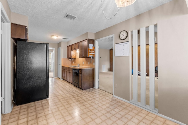 kitchen featuring sink, a textured ceiling, backsplash, dark brown cabinetry, and black appliances