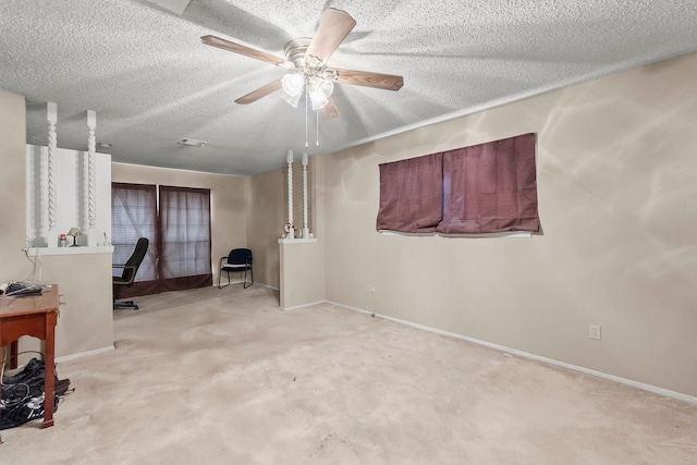 interior space with a textured ceiling, light carpet, and ceiling fan