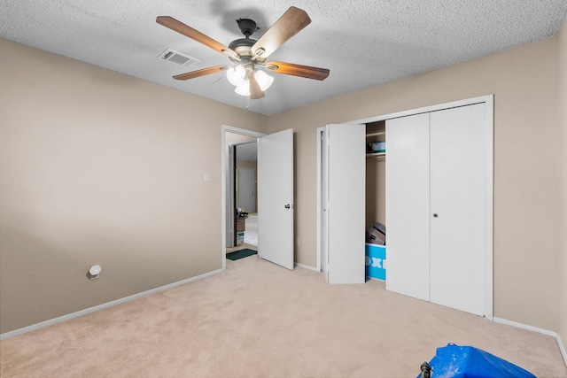 unfurnished bedroom with a closet, a textured ceiling, ceiling fan, and light carpet