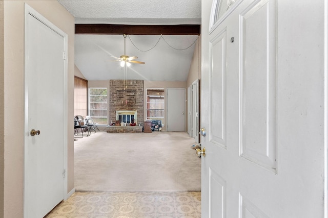 interior space featuring ceiling fan, vaulted ceiling with beams, a brick fireplace, and light carpet