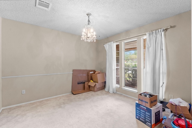 misc room featuring a textured ceiling, an inviting chandelier, and carpet