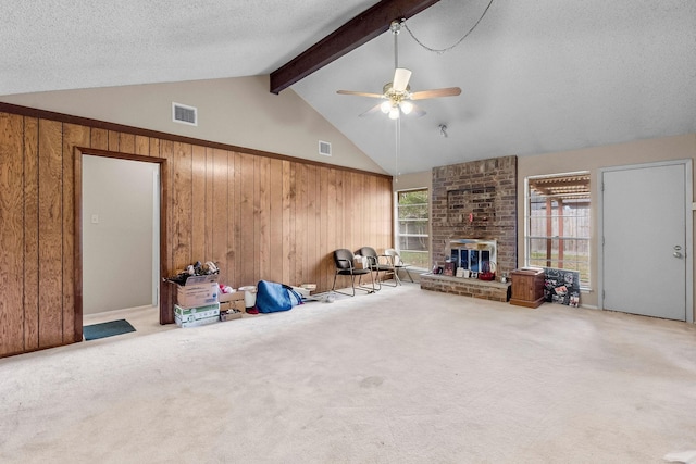 unfurnished living room with wood walls, carpet floors, ceiling fan, a fireplace, and a textured ceiling