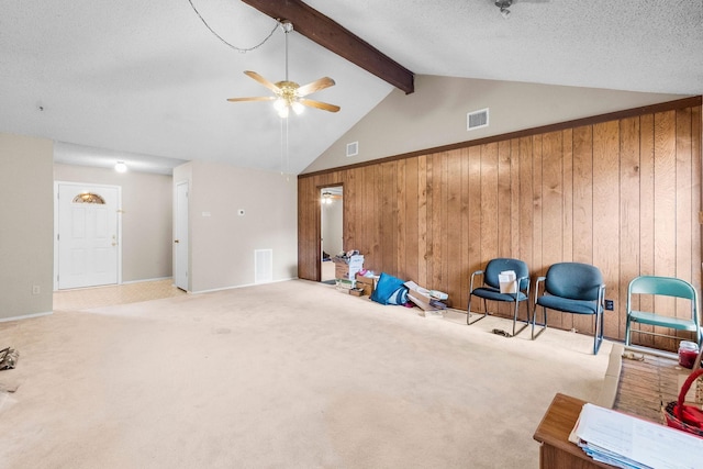 exercise area featuring lofted ceiling, a textured ceiling, wooden walls, and light carpet