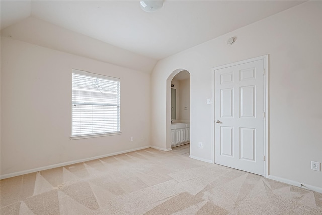 carpeted empty room with vaulted ceiling