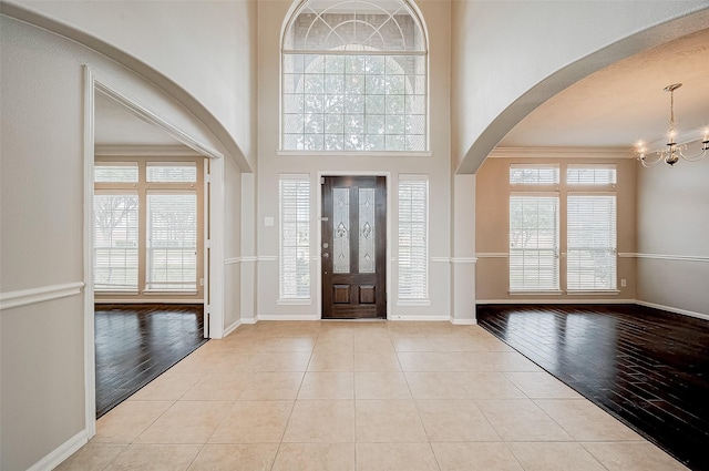 tiled entrance foyer with a notable chandelier and crown molding