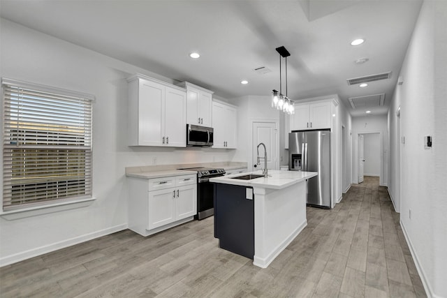 kitchen featuring sink, white cabinets, hanging light fixtures, a center island with sink, and appliances with stainless steel finishes