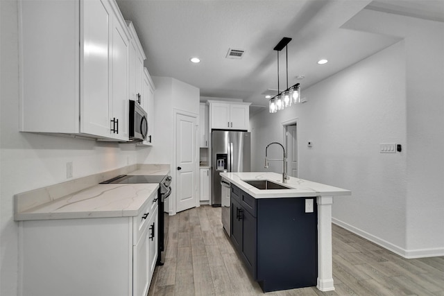 kitchen with sink, stainless steel appliances, white cabinetry, pendant lighting, and a kitchen island with sink