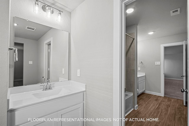 bathroom with visible vents, walk in shower, vanity, and wood finished floors