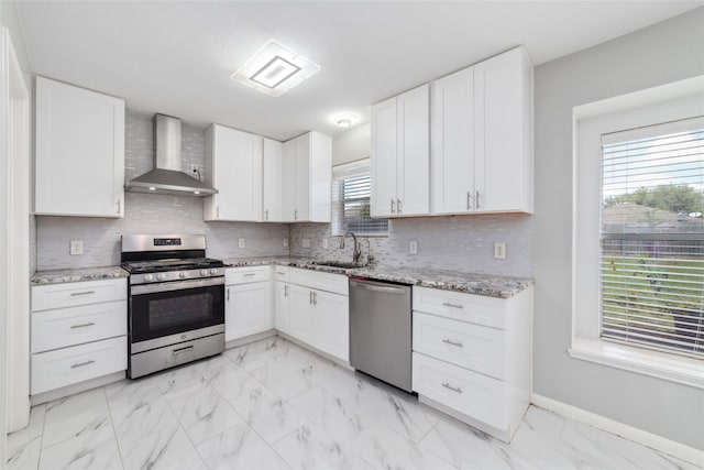 kitchen with appliances with stainless steel finishes, white cabinetry, sink, and wall chimney exhaust hood