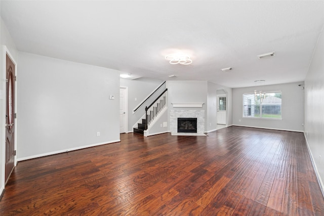 unfurnished living room featuring dark hardwood / wood-style flooring and a stone fireplace