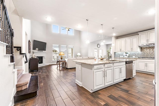 kitchen featuring white cabinetry, ceiling fan, a kitchen island with sink, pendant lighting, and light stone counters