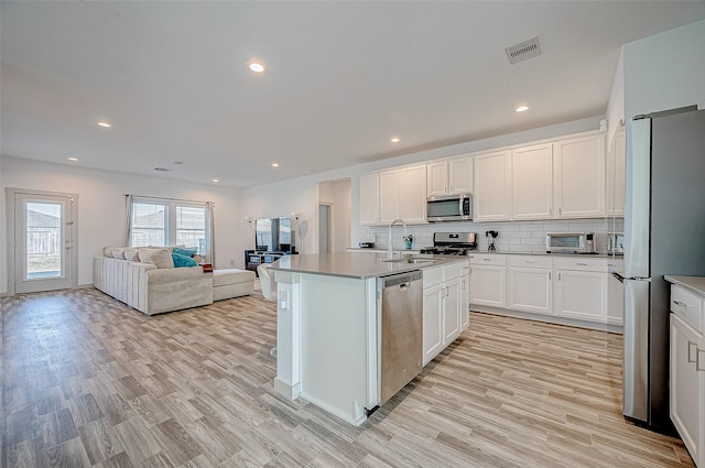 kitchen with sink, stainless steel appliances, white cabinetry, and a kitchen island with sink