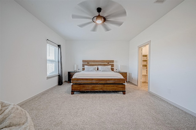 carpeted bedroom with a walk in closet and ceiling fan