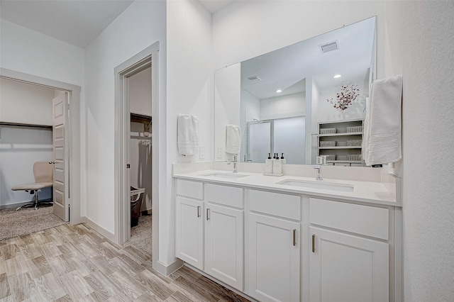 bathroom with hardwood / wood-style flooring, a shower with shower door, and vanity