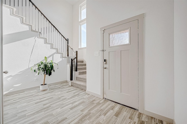 entrance foyer with light wood-type flooring and a towering ceiling