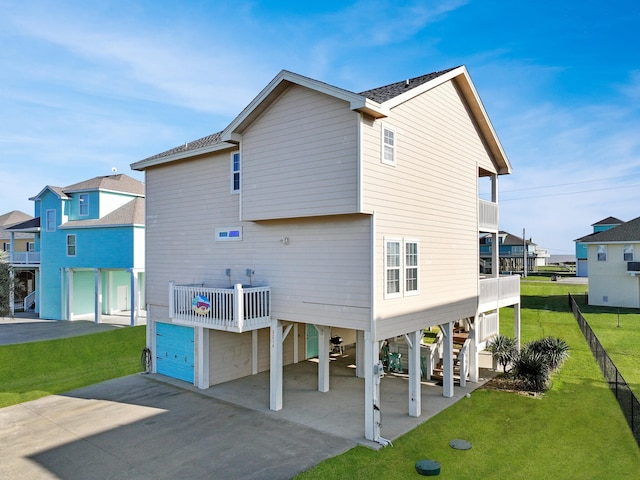 back of house featuring a garage, a yard, a balcony, and a carport