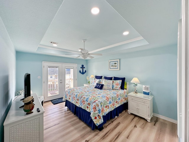 bedroom with ceiling fan, light hardwood / wood-style floors, a raised ceiling, and access to outside