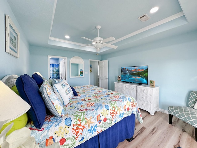 bedroom with a raised ceiling, ceiling fan, crown molding, and light hardwood / wood-style flooring