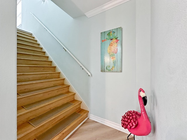 staircase with crown molding and hardwood / wood-style floors