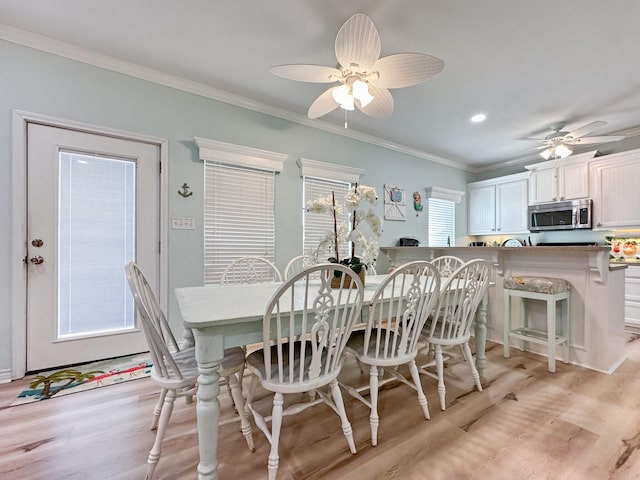 dining room with ceiling fan, a healthy amount of sunlight, ornamental molding, and light wood-type flooring