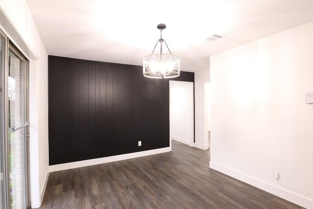 unfurnished room with a notable chandelier and dark wood-type flooring