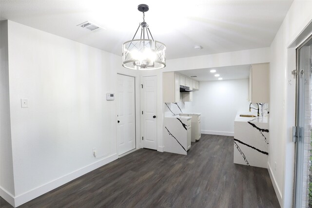 kitchen featuring dark wood-type flooring, a chandelier, hanging light fixtures, white cabinetry, and sink