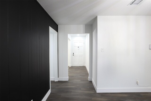 hall with a textured ceiling and dark wood-type flooring