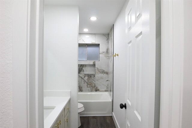 full bathroom with wood-type flooring, tiled shower / bath, vanity, and toilet