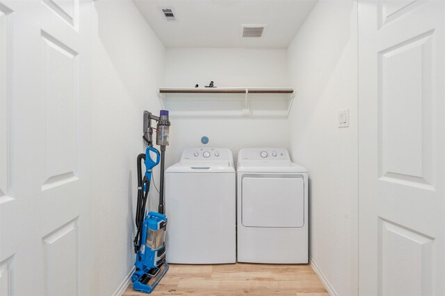 laundry room featuring light hardwood / wood-style floors and separate washer and dryer