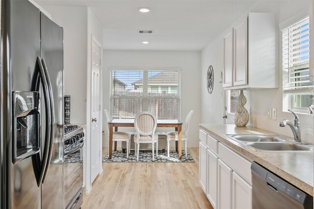 kitchen featuring light hardwood / wood-style flooring, white cabinets, black appliances, and sink