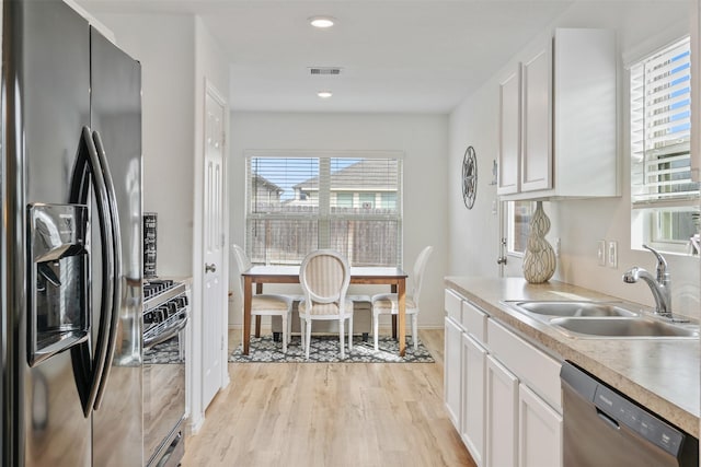 kitchen with visible vents, appliances with stainless steel finishes, light countertops, light wood-type flooring, and a sink