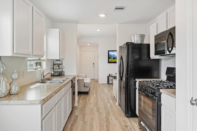 kitchen with sink, light hardwood / wood-style flooring, black appliances, and white cabinetry