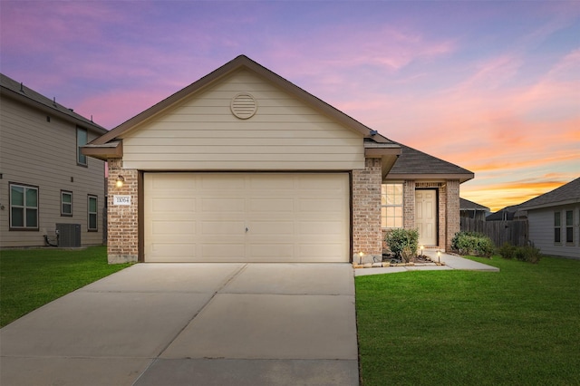 view of front of house featuring a lawn, central air condition unit, and a garage