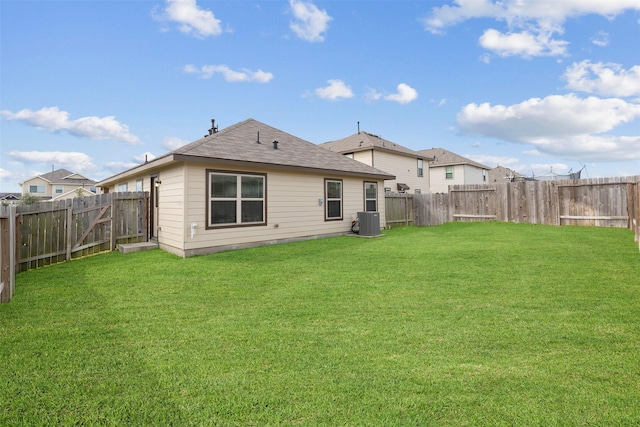 rear view of property with a fenced backyard, central AC, a shingled roof, and a lawn