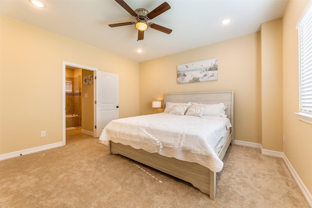 bedroom featuring ensuite bath, light carpet, and ceiling fan