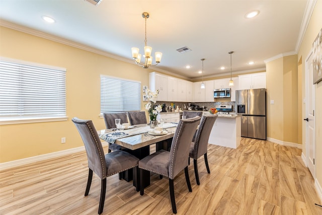 dining space featuring crown molding, a chandelier, and light hardwood / wood-style flooring