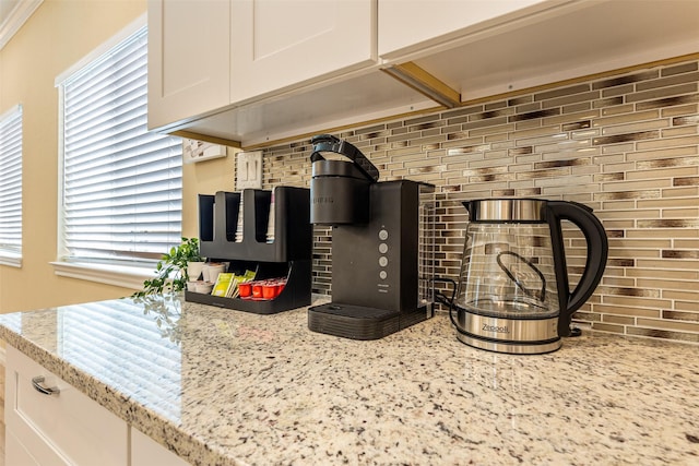 room details with light stone countertops, white cabinets, and tasteful backsplash