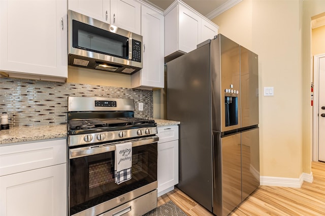 kitchen featuring white cabinetry, backsplash, light stone countertops, crown molding, and appliances with stainless steel finishes