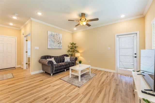 living room with ornamental molding, ceiling fan, light wood-type flooring, and a healthy amount of sunlight