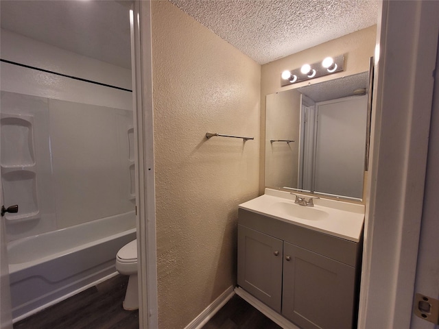 bathroom featuring toilet, vanity, a textured wall, wood finished floors, and a textured ceiling