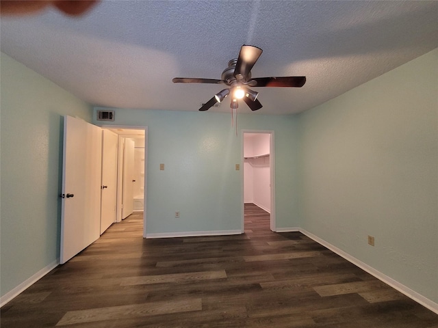 unfurnished bedroom with dark wood-style floors, visible vents, a textured ceiling, and baseboards