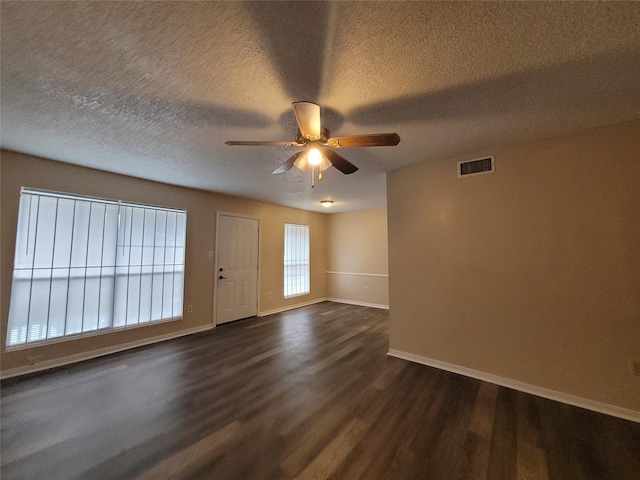 spare room with a ceiling fan, visible vents, baseboards, dark wood-style flooring, and a textured ceiling