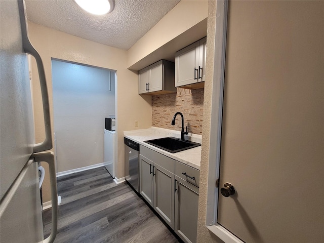 kitchen with tasteful backsplash, a sink, dishwasher, freestanding refrigerator, and dark wood-style flooring