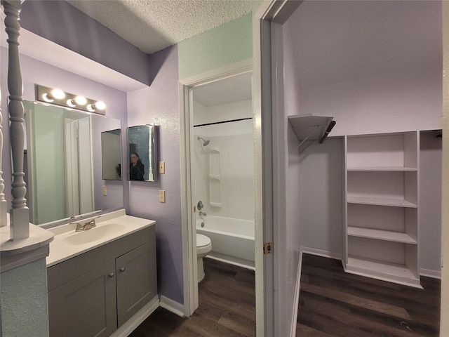 full bath featuring vanity, wood finished floors, a textured ceiling, bathing tub / shower combination, and toilet